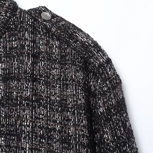 Macro detail of black and white tweed jacket fabric with silver metal button decor