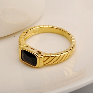 Macro view of gold-plated ring with rectangular black zircon and diagonal textured grooves