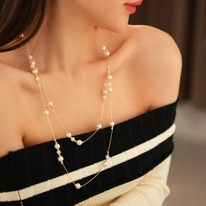 Detail of layered gold chain necklace featuring white artificial pearls on a model
