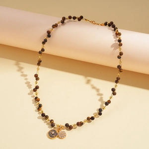 Detail of 18k gold plated beaded necklace featuring brown tiger eye stones and floral charms