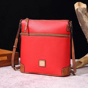 Detail of red pebbled leather crossbody bag with brown trim and gold logo hardware