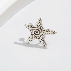 Macro shot of silver starfish ear clip with vintage texture and spiral detail