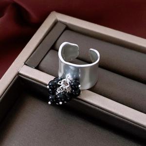 Detail of irregular silver wide ring featuring black beaded charms and matte finish texture