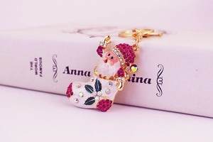 Detail of pink rhinestone Santa boot keychain charm on a book with gold plating