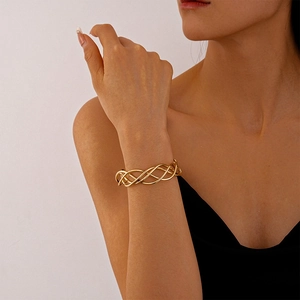 Detail of a golden woven mesh cuff bracelet on wrist showing geometric metal texture