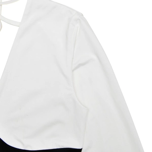 Detail shot of a deep V-neck sleeveless white dress with contrasting black trim accents