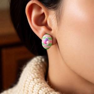 Close-up of oval striped earring in green and pink stripes with colorful bead accents