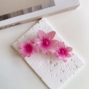 Close-up of pink floral hair claw clip with gradient petals on a white stone base