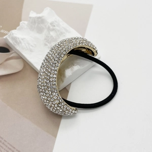 Detail of a golden alloy hair ring with pavé rhinestones on a black elastic cord
