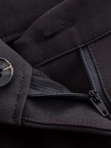 Gros plan détaillé du bouton effet marbre et de la fermeture éclair sur le pantalon noir