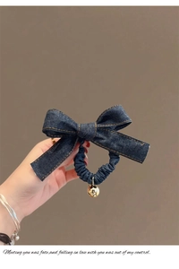 Gros plan d'un chouchou nud en denim bleu foncé avec pendentif boule en métal doré