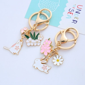 Porte-clés mignons avec pendentifs émaillés lapin et chat et anneaux dorés sur fond blanc
