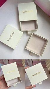 Detailed macro view of cream jewelry drawer box with ribbon handle and gold logo