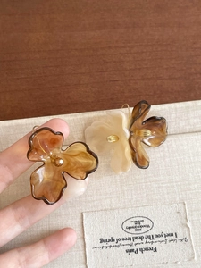 Close-up of bohemian amber and cream acrylic flower earrings with golden stamen detail