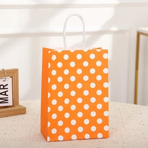 Bolsa de papel naranja con lunares blancos y asas tejidas para fiestas de cumpleaños
