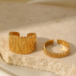Detail view of two gold stainless steel rings with irregular bark and chain textures