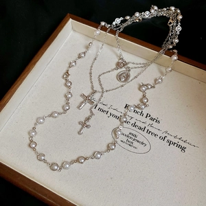 Macro shot of silver-colored layered cross and religious portrait pendants with pearls