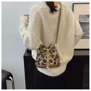 Detail of plush leopard print bucket bag with gold chain drawstring and pearl accents