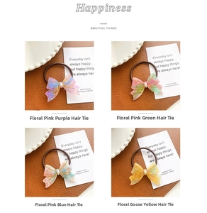 Detail of acetate floral bow hair ties in four pastel colors on leather background