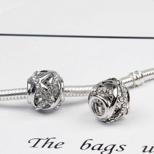 Detailed macro view of silver hollow woven charms set with rhinestones on a snake chain