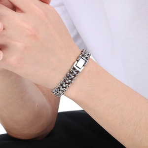 Detailed view of silver stainless steel wheat chain bracelet worn on a man's wrist