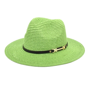 Detail of neon green straw hat with a slim black band and golden buckle accent