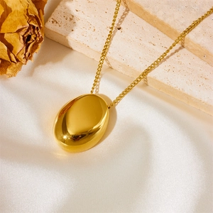 Vintage oversized gold water drop oval pendant necklace on elegant cream silk background