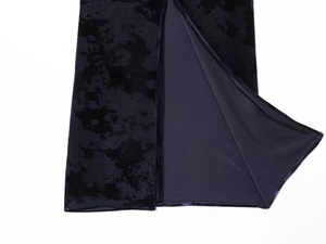 Detailed close-up of high side slit on black velvet midi dress with soft fabric texture