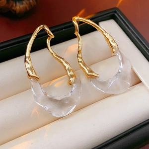 Detail of 18k gold plated irregular resin earrings on a cream jewelry display case