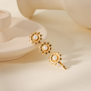 Detail of 18K gold-plated hair clip with three sun flowers and embedded pearls on ceramic