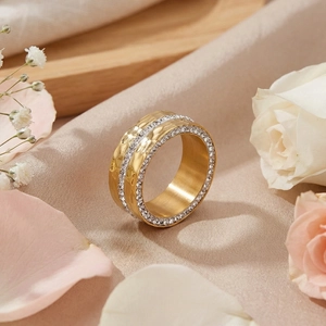 Macro shot of gold hammered wide band ring with pave set sparkling zircons on pink silk
