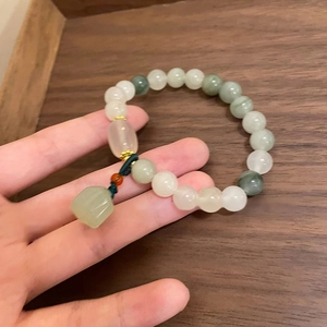 Détail d'un bracelet en perles de jade avec pendentif lotus tenu à la main