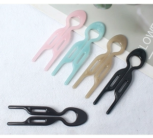 Close-up of multicolored U-shaped wavy hair pins in acetate finish on white linen fabric