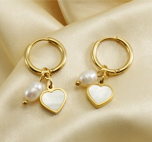 Close-up of gold stainless steel hoop earrings with pearl and mother of pearl heart charms