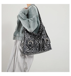 Detail of grey leopard print hobo bag featuring metal ring accents and front pockets