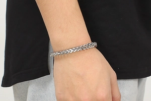 Macro view of silver Franco chain bracelet in stainless steel on a person's wrist