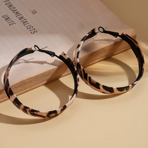 Macro shot of leopard print hoop earrings resting on vintage book with warm soft lighting