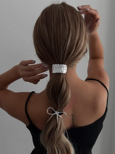 Rear view of model wearing silver metal hair bow and striped ponytail cuff accessories