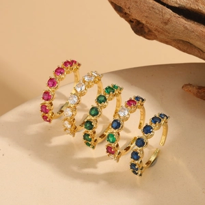 Detailed view of five adjustable gold rings with colorful cubic zirconia in claw settings