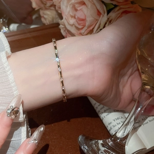 Detail of elegant gold bracelet with zircon stones worn against a floral aesthetic background