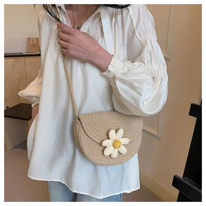 Detail of khaki woven crossbody bag with a 3D white daisy and yellow smiley face