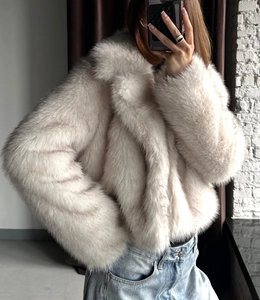 Detail of short faux fox fur jacket in beige featuring a plush texture and wide lapel