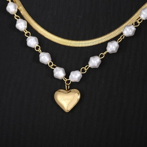 Detail of double-layer necklace with gold snake chain, baroque pearls and love heart charm