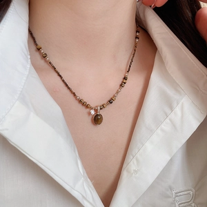Close-up of tiger eye pendant necklace with zircon accents on a beaded chain for women