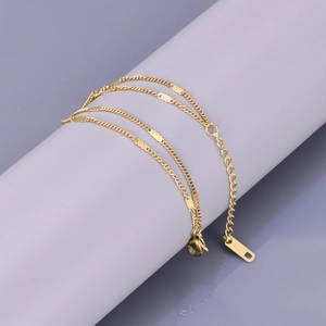 Detailed view of dual-layer gold bracelet featuring K18 hallmark tag on minimalist chain