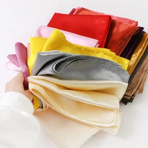 Close-up of stacked colorful satin square scarves showing silky texture and glossy finish