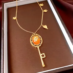 Vintage 18K gold key pendant necklace with orange stone and decorative flower charms