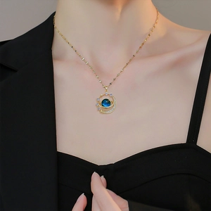 Close-up of gold planet pendant with blue stone and cubic zirconia on a delicate chain