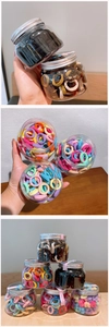 Close-up of assorted colorful elastic hair ties in a clear jar with a silver screw lid