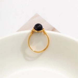 Detail of handmade gold wire-wrapped ring featuring a sparkling blue goldstone bead